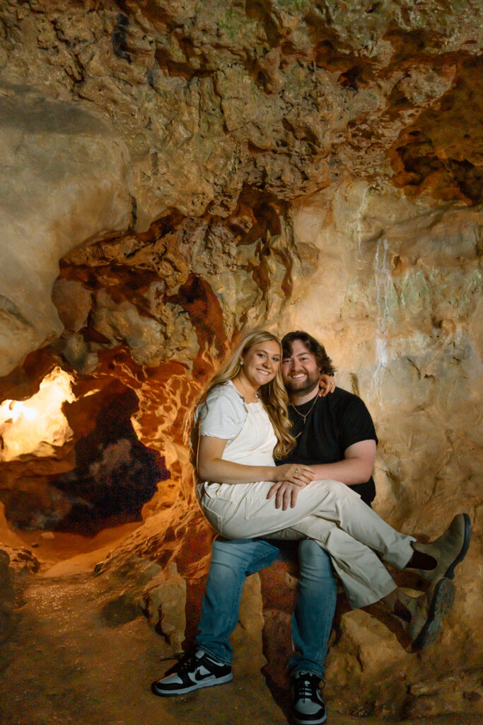 Couple sitting together in a Cave for engagement photos. Cave Springs, Georgia